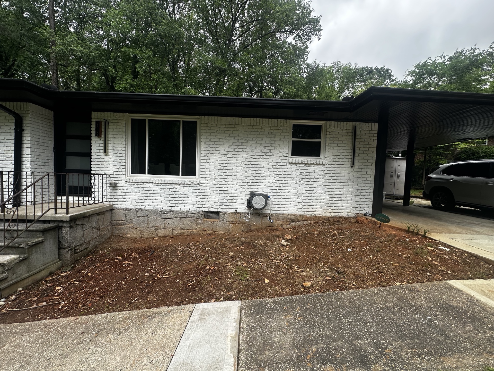 Bare dirt by front of house near carport